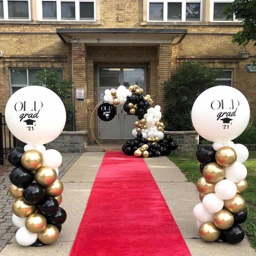graduation party idea door entrance decorated with balloons and red carpet.